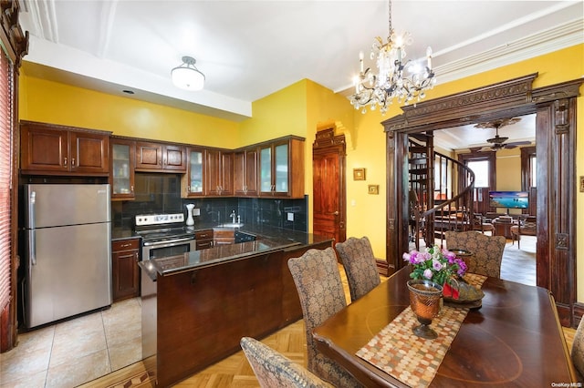 kitchen with sink, tasteful backsplash, light tile patterned floors, ceiling fan with notable chandelier, and appliances with stainless steel finishes