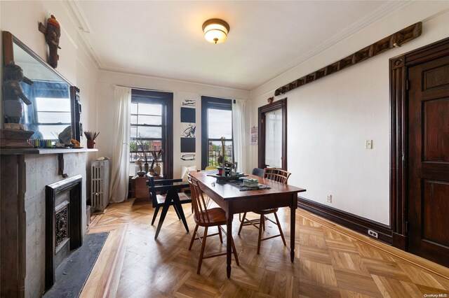 dining space featuring a wealth of natural light, radiator heating unit, light parquet flooring, and ornamental molding