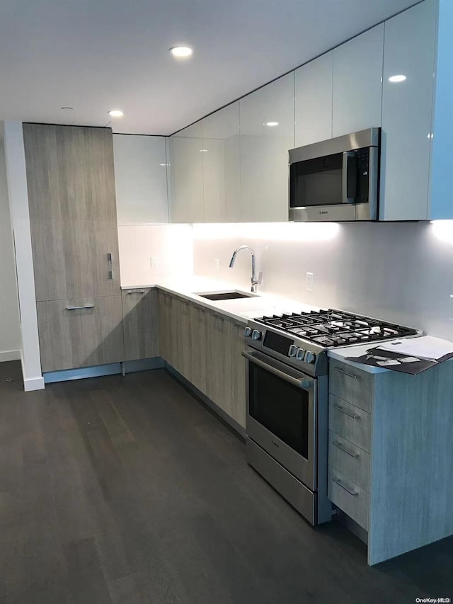 kitchen with white cabinetry, sink, stainless steel appliances, and dark hardwood / wood-style floors