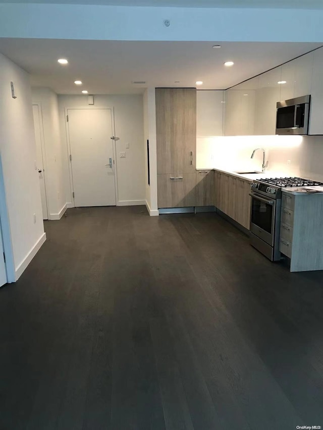 kitchen featuring white cabinets, appliances with stainless steel finishes, dark hardwood / wood-style flooring, and sink