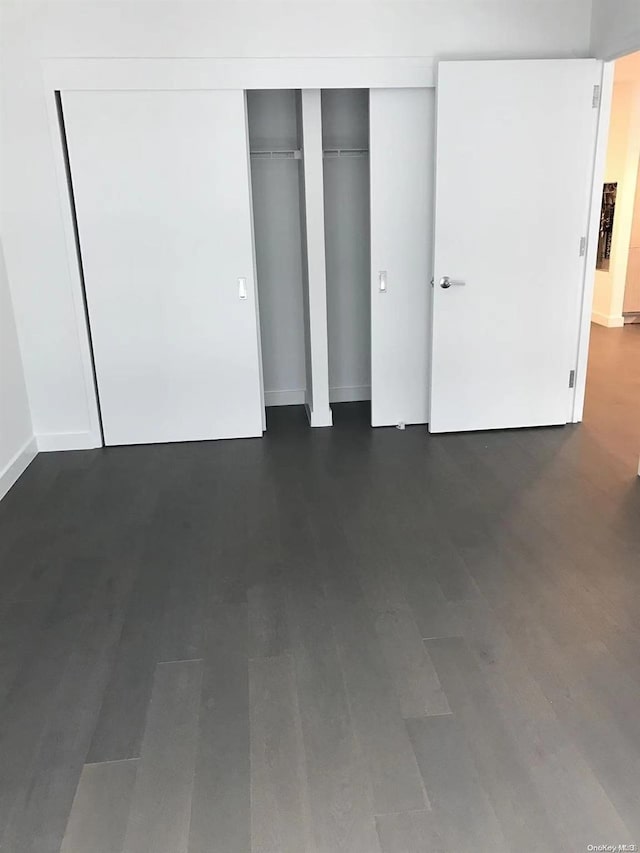 unfurnished bedroom featuring dark hardwood / wood-style flooring and a closet