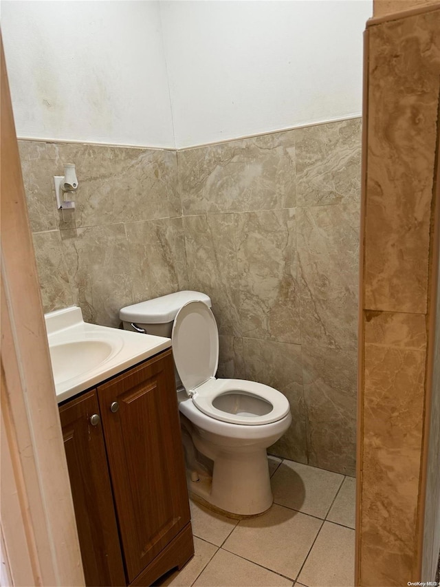 bathroom with tile patterned flooring, vanity, toilet, and tile walls