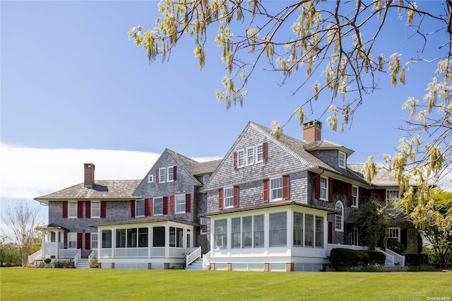 back of property with a yard and a sunroom