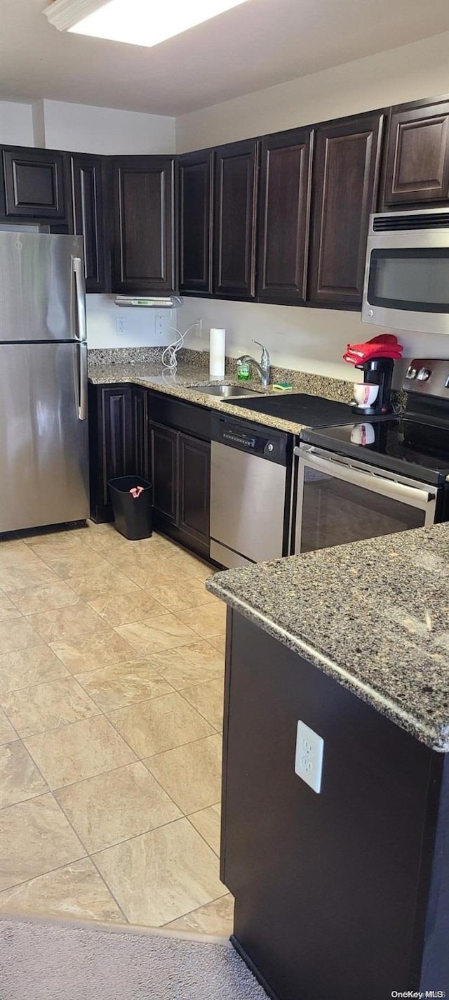 kitchen featuring dark brown cabinetry, light stone countertops, sink, and appliances with stainless steel finishes