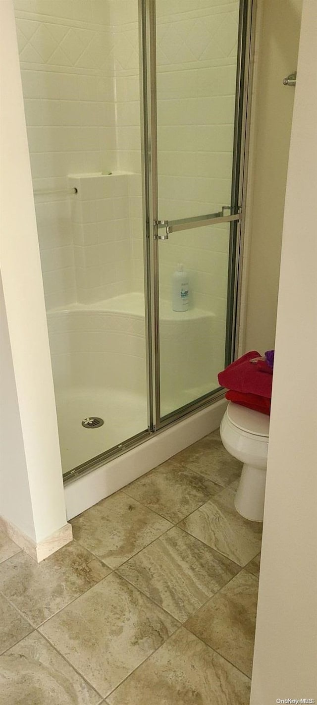 bathroom with a shower with door and toilet