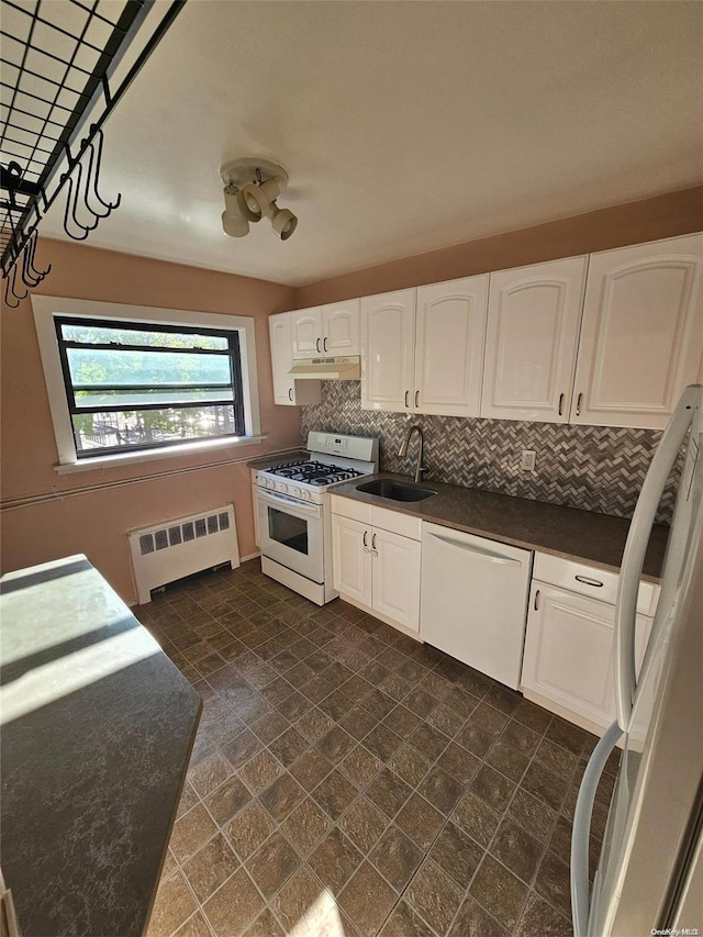 kitchen with tasteful backsplash, radiator, white appliances, sink, and white cabinetry