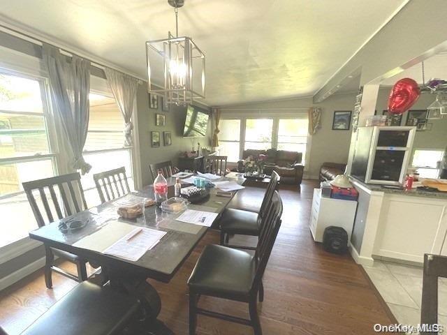 dining space featuring hardwood / wood-style floors, an inviting chandelier, and lofted ceiling