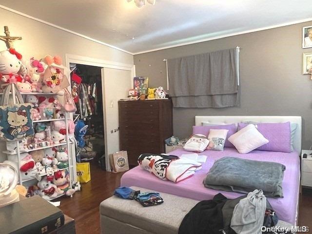 bedroom featuring dark hardwood / wood-style flooring, crown molding, and a closet