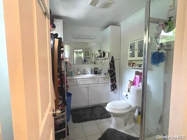 bathroom featuring toilet, vanity, tile patterned floors, and an enclosed shower