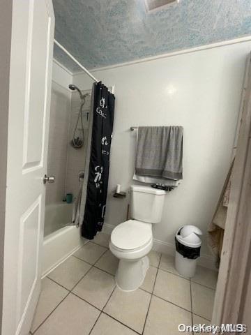 bathroom with tile patterned flooring, toilet, and shower / tub combo