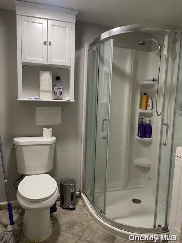 bathroom with tile patterned flooring, toilet, and an enclosed shower