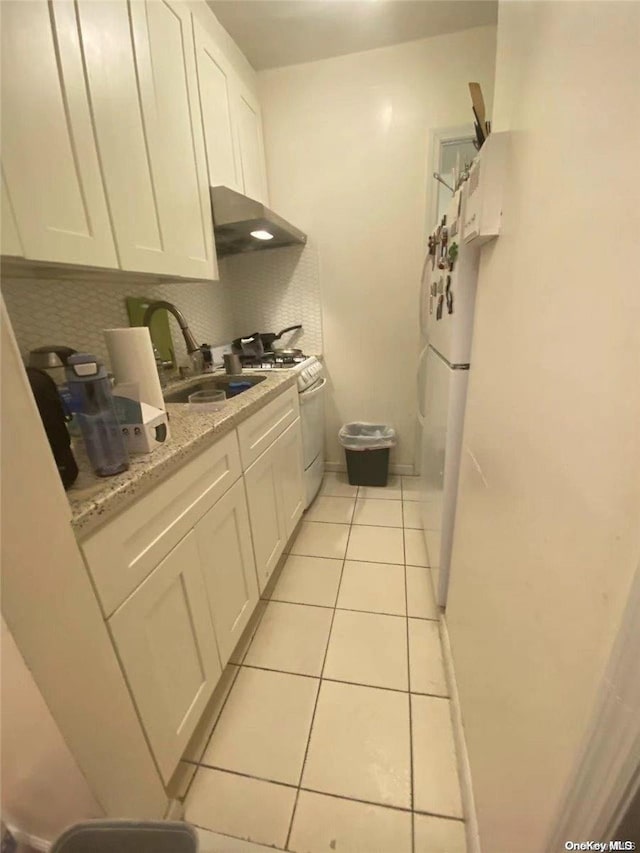 kitchen featuring light stone countertops, white cabinets, light tile patterned flooring, and white appliances