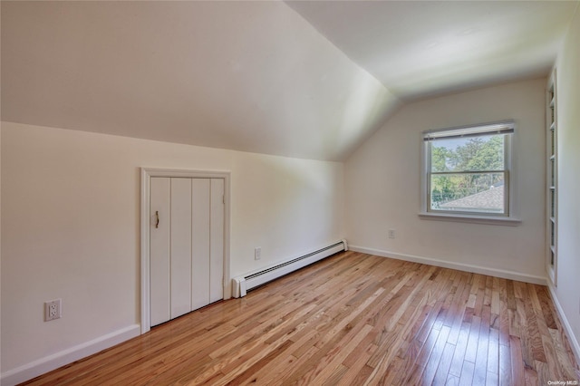 additional living space featuring light wood-type flooring, baseboard heating, and vaulted ceiling