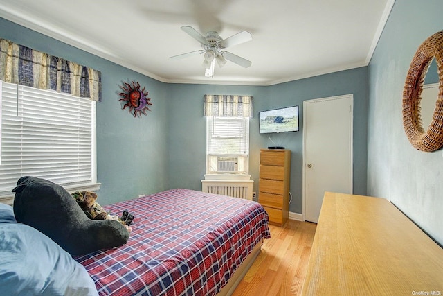 bedroom featuring ceiling fan, radiator heating unit, crown molding, and light hardwood / wood-style flooring