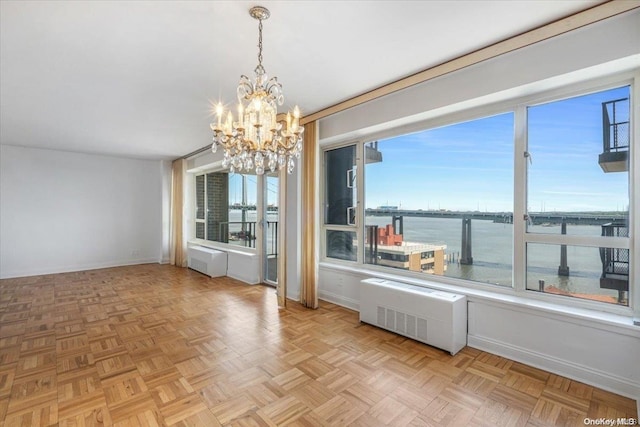 unfurnished dining area featuring light parquet floors, a water view, an inviting chandelier, and radiator