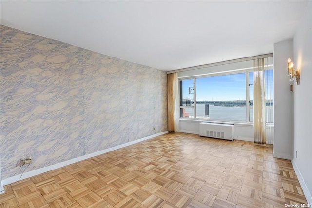 unfurnished room featuring radiator, light parquet flooring, and a water view