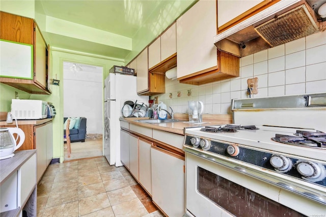 kitchen featuring decorative backsplash, white appliances, ventilation hood, sink, and white cabinetry