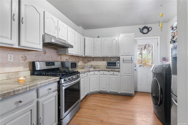 kitchen with washer / dryer, light wood-type flooring, stainless steel appliances, and white cabinetry