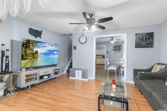 living room with ceiling fan with notable chandelier and hardwood / wood-style flooring