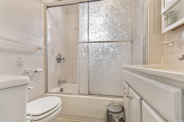 bathroom with toilet, tile walls, and combined bath / shower with glass door