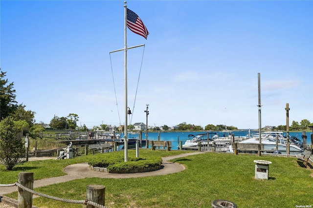 view of property's community featuring a lawn, a water view, and a boat dock