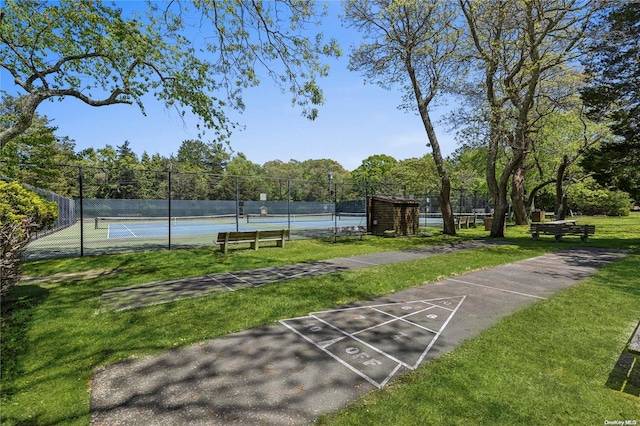 view of property's community with a lawn and tennis court