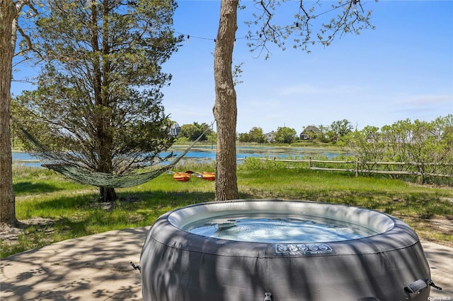 view of patio / terrace featuring a water view and a hot tub