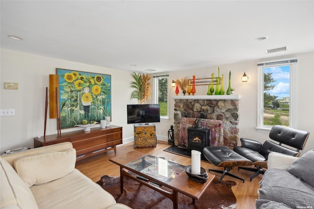 living room featuring hardwood / wood-style flooring, a wood stove, and plenty of natural light