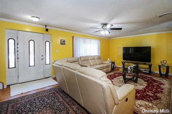 living room with wood-type flooring, ceiling fan, and crown molding