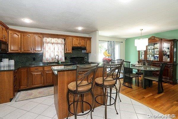 kitchen featuring black appliances, decorative light fixtures, light hardwood / wood-style flooring, decorative backsplash, and a notable chandelier