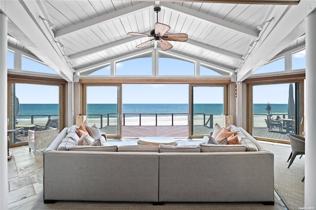 living room featuring ceiling fan, a water view, lofted ceiling with beams, and a view of the beach