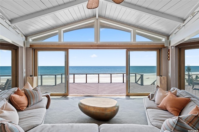 living room with lofted ceiling with beams, a water view, and a healthy amount of sunlight