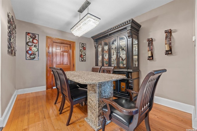 dining space with light hardwood / wood-style flooring and an inviting chandelier