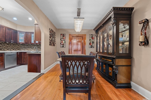 dining room featuring a chandelier, sink, and light hardwood / wood-style flooring