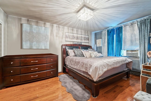 bedroom featuring a chandelier, light wood-type flooring, and cooling unit