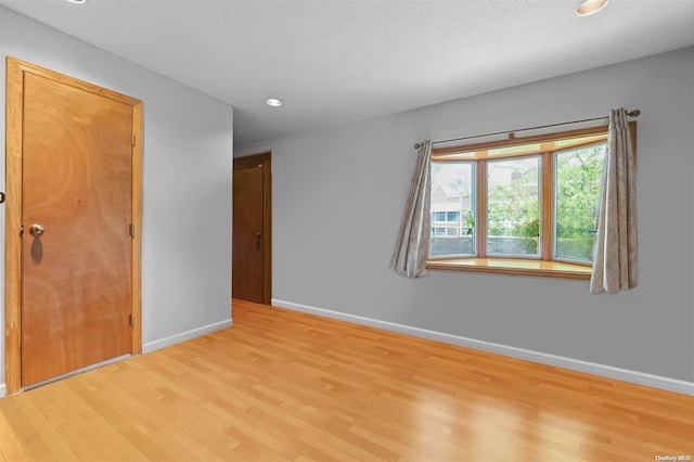 spare room with light hardwood / wood-style floors and a textured ceiling