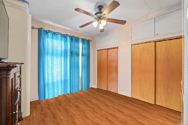 unfurnished bedroom featuring light wood-type flooring, two closets, and ceiling fan