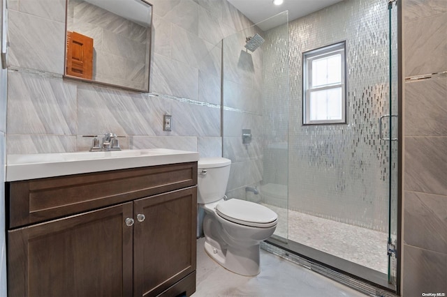 bathroom with a shower with door, vanity, tile walls, and toilet