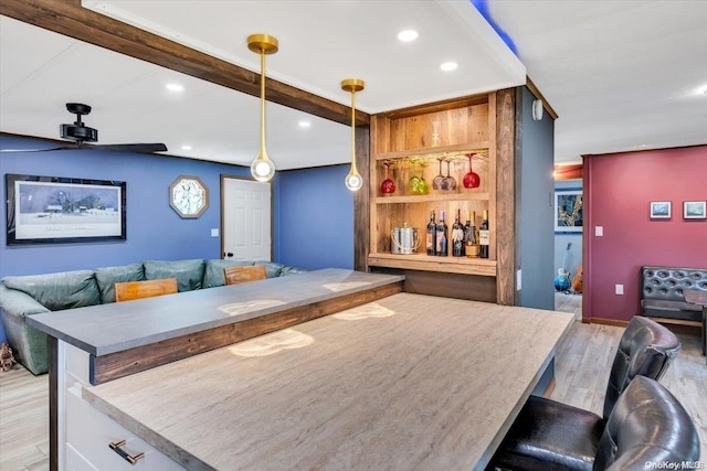 bar with pendant lighting, ceiling fan, and light hardwood / wood-style flooring