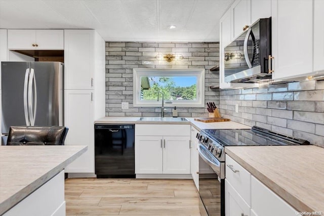 kitchen featuring sink, light hardwood / wood-style flooring, appliances with stainless steel finishes, tasteful backsplash, and white cabinetry