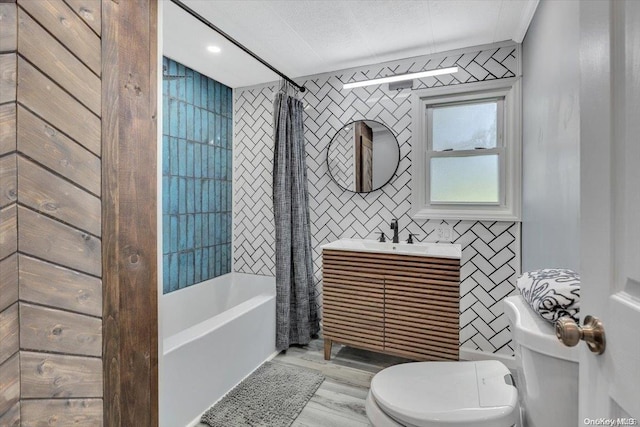 full bathroom featuring hardwood / wood-style floors, vanity, toilet, shower / bath combo with shower curtain, and tile walls