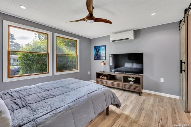 bedroom with light hardwood / wood-style floors, an AC wall unit, and ceiling fan