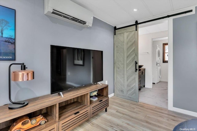 living room featuring a barn door, a wall mounted AC, and light hardwood / wood-style floors