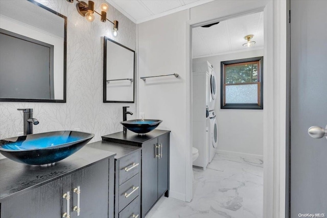 bathroom featuring toilet, vanity, crown molding, and stacked washer and clothes dryer