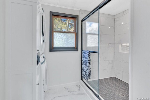 bathroom with an enclosed shower and stacked washer and clothes dryer