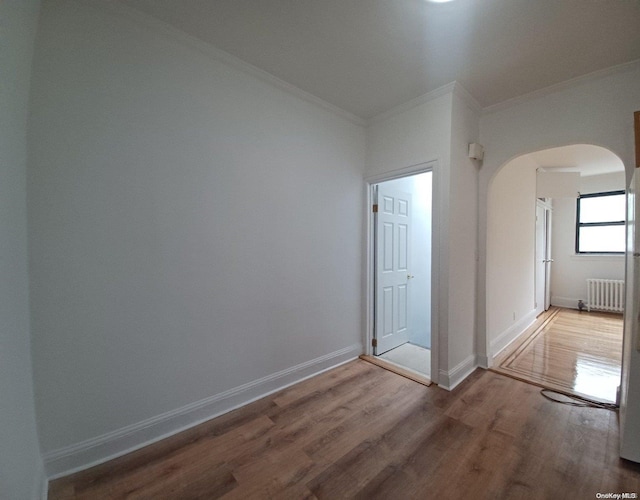 unfurnished room with hardwood / wood-style floors, radiator, and crown molding