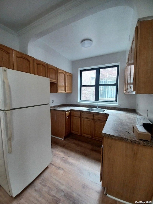 kitchen featuring white refrigerator, light hardwood / wood-style flooring, crown molding, and sink