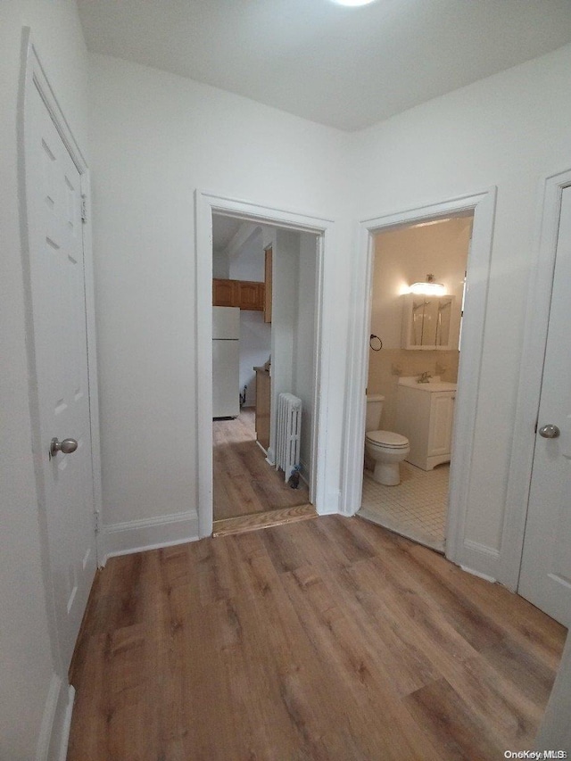 corridor featuring radiator and light hardwood / wood-style flooring