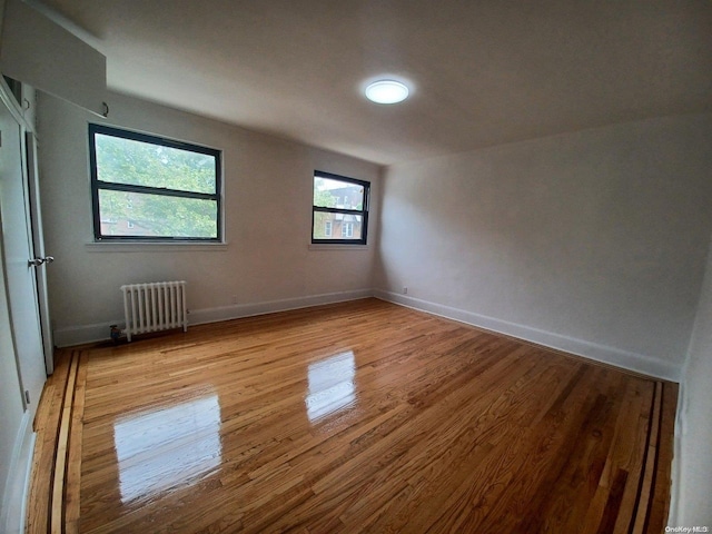 spare room featuring radiator and light hardwood / wood-style flooring