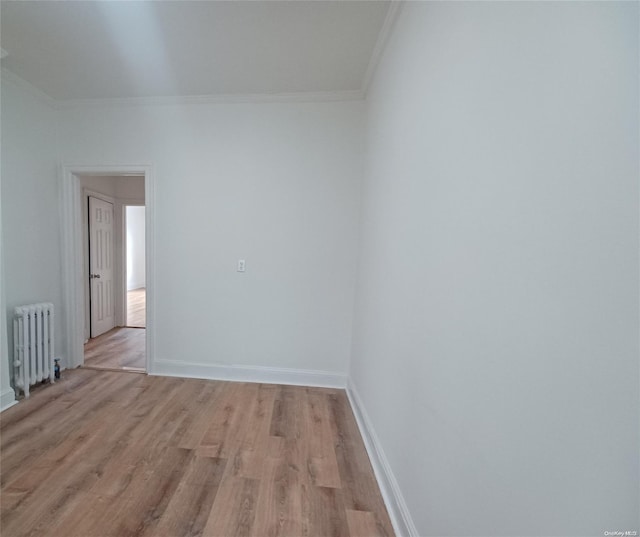 spare room featuring light hardwood / wood-style flooring, radiator, and crown molding